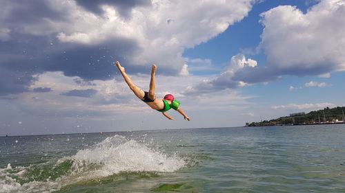 Person paragliding in sea against sky