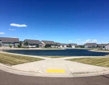 Road by houses against blue sky