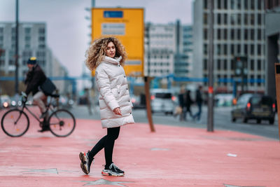 Portrait of young woman walking on street in city