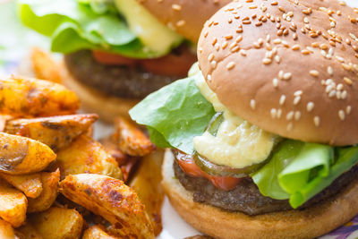 Close-up of burgers and fried potatoes on plate