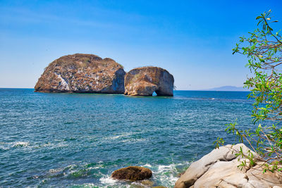 Rocks in sea against blue sky