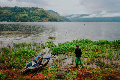 Rear view of people looking at lake against sky