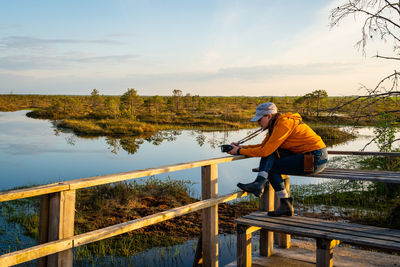 Side view of man fishing on lake against sky