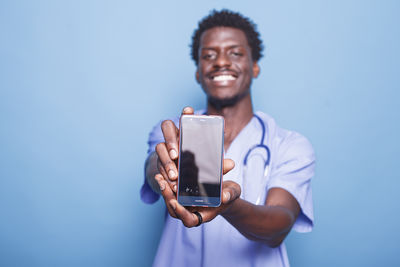 Young woman using mobile phone against blue background