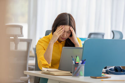 Depressed businesswoman wearing mask sitting at office