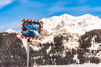 Winter road reflecting in a frozen mirror with snow-capped mountains in the background. schladming