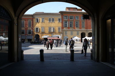 People walking on street seen from arch