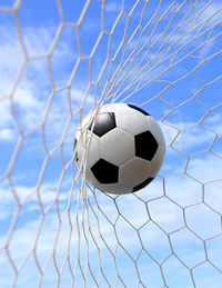 Soccer ball hitting in goal post against blue sky