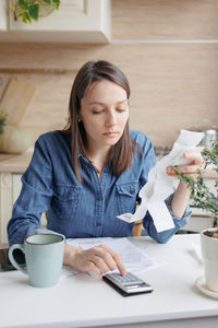 Portrait of young woman using mobile phone while sitting on table