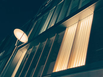 Low angle view of illuminated street light against building at night