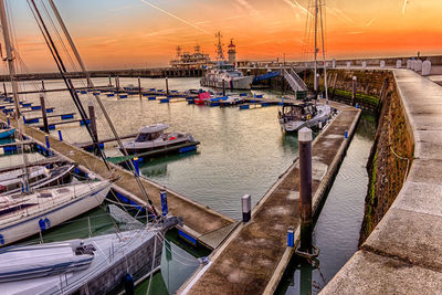 High angle view of sailboats moored at harbor during sunset