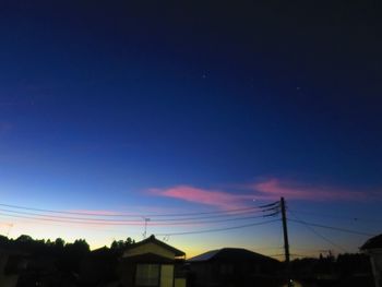 Low angle view of silhouette electricity pylons against sky at sunset