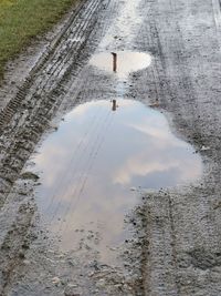 Reflection of clouds in puddle on road