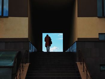 Rear view of silhouette man walking on staircase of building