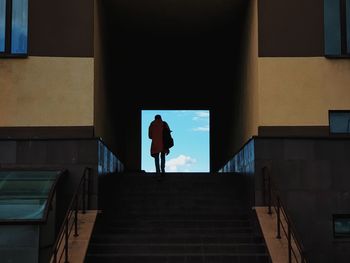 Rear view of man walking on staircase of building