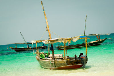 Fishing boats moored in sea against clear sky