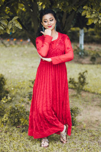 Portrait of young woman standing against plants