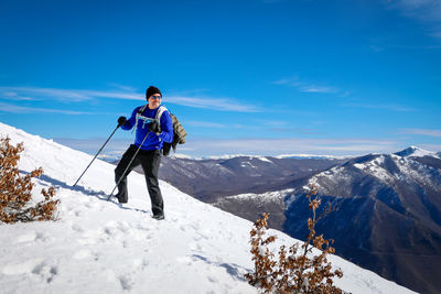 Full length of woman skiing on snowcapped mountain against sky