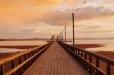 View of pier in sea at sunset