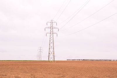 Electricity pylon on field against sky