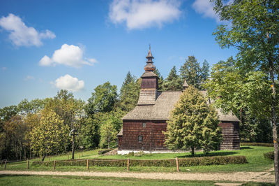 Built structure by trees on field against sky