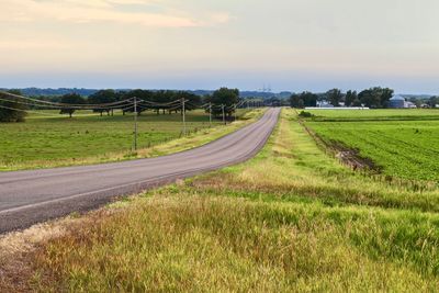 Road amidst field against sky