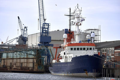 Cranes at harbor against sky