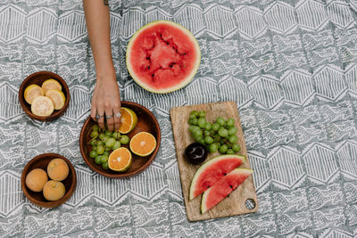 High angle view of woman touching fruits in plate