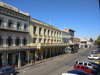 Cars on road by buildings against clear blue sky