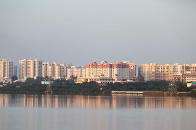 Buildings by lake against clear sky