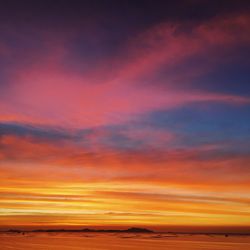 Scenic view of sea against dramatic sky during sunset