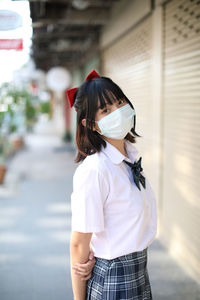 Portrait of young woman wearing mask standing outdoors