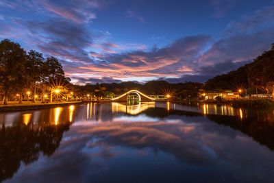 Illuminated bridge over river against sky at night