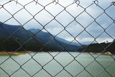 Scenic view of river seen through chainlink fence
