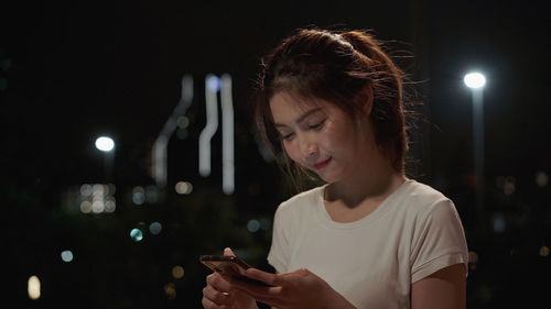 Young woman using mobile phone at night