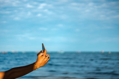 Midsection of person by sea against sky