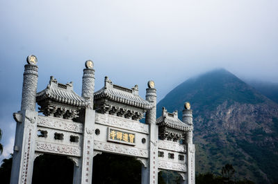 Traditional built structure by mountain against sky