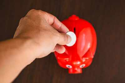 Close-up of hand holding red ball on table