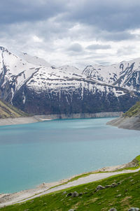 Scenic view of lake by snowcapped mountains against sky