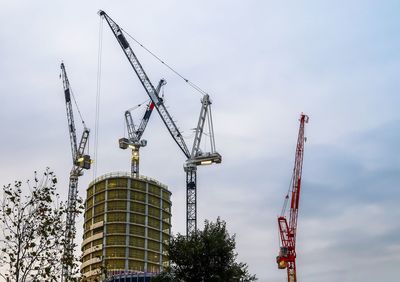 Low angle view of cranes at construction site against sky