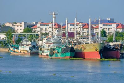 Boats moored at harbor against clear blue sky