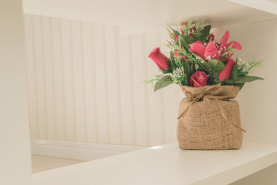 Close-up of flower vase on table against wall at home