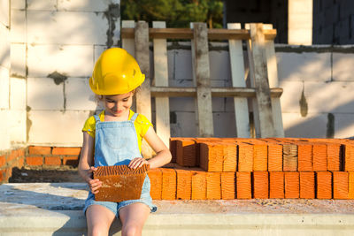 Cute girl wearing hard had holding brick at construction site