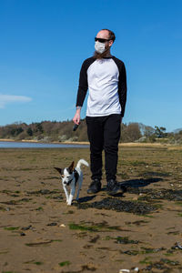 Full length of dog standing on landscape against sky