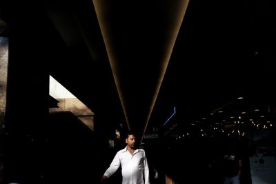 Portrait of young man standing on bridge at night