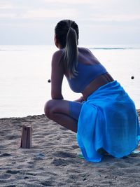 Rear view of woman sitting on beach