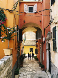 Rear view of people walking on footpath amidst buildings