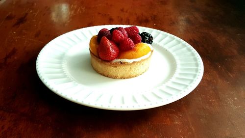 High angle view of fruit tart in plate on wooden table