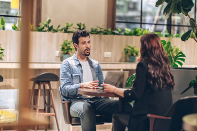 Young man using phone while sitting on chair