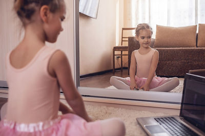 Pretty young ballerina practicing classic choreography during online class, social distance